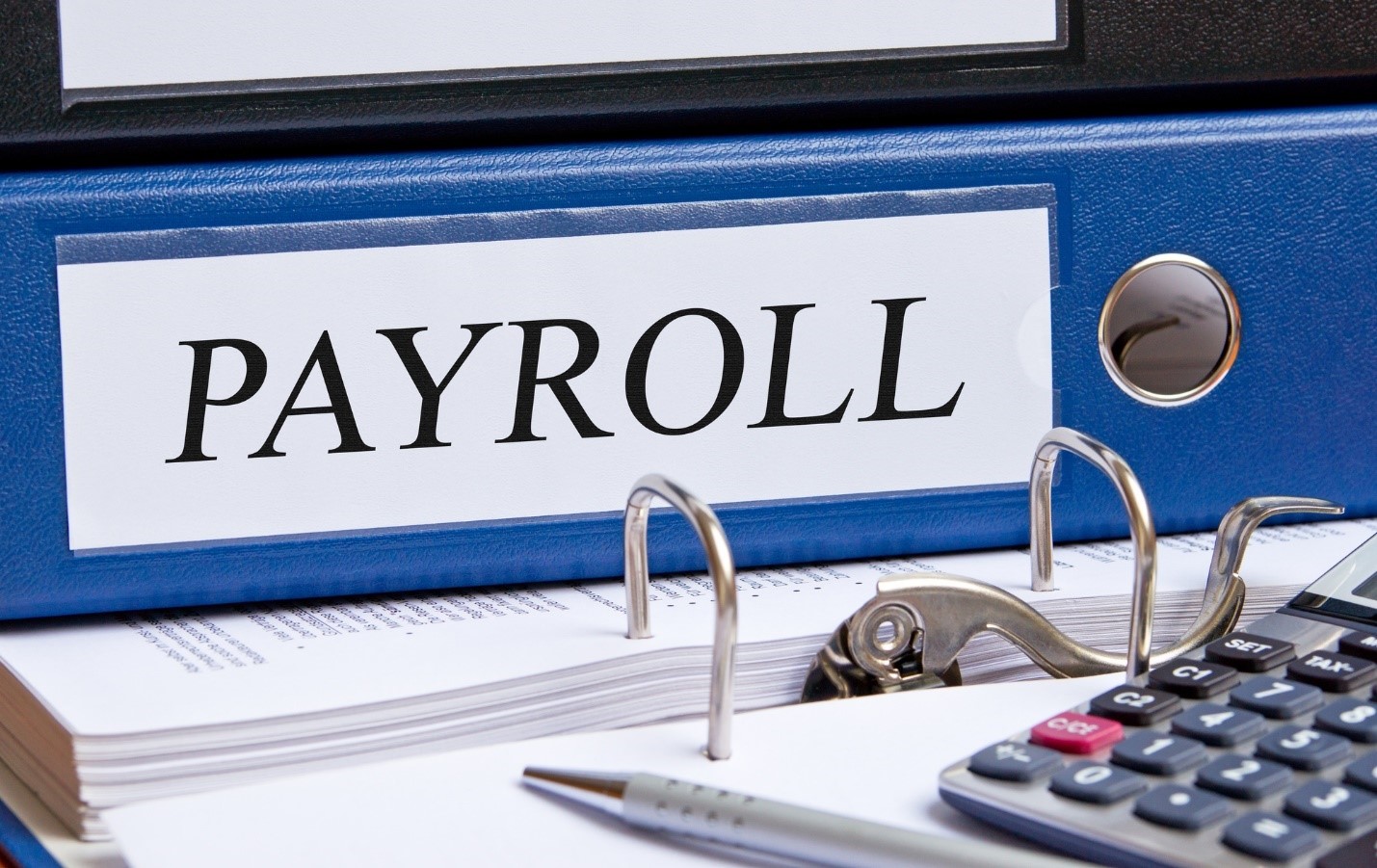 Close up photo of a blue payroll binder on a desktop